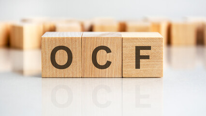 ocf - letters on wooden cubes. business as usual concept image. front view