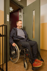 Disabled man on wheel chair using elevator in apartment house