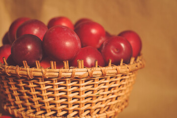 Composite photo of red plums in a basket standing on a table. Craft paper. Healthy eating. Fruit.