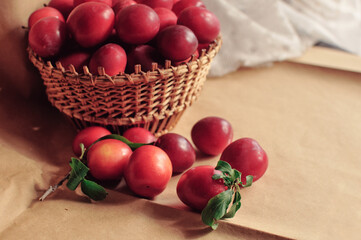 Composite photo of red plums in a basket standing on a table. Craft paper. Healthy eating. Fruit.