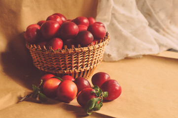 Fototapeta na wymiar Composite photo of red plums in a basket standing on a table. Craft paper. Healthy eating. Fruit.