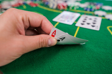 player shows two play card aces on a green table in a casino wirh chips.