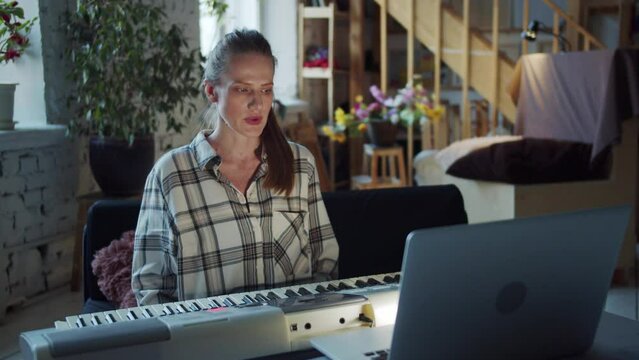 A woman tunes a synthesizer using lessons from the Internet