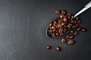 spoon with coffee on a black background.  spoon with coffee beans. coffee bean. Texture  of roasted coffee beans .