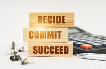 On the reports is a pen, calculator, clips and wooden boards with the inscription - DECIDE COMMIT...