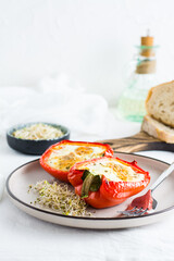 Bell pepper halves baked with egg and microgreens on a plate on the table. Flexitarian organic diet. Vertical view. Copy space