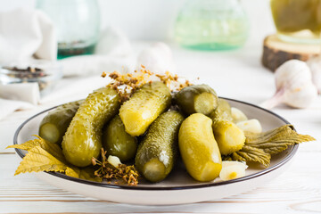 Ready-to-eat pickled cucumbers on a plate and ingredients for cooking on a wooden table. Homemade snacks.
