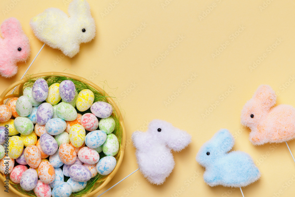 Poster easter composition of eggs in a basket of toy rabbits on a yellow background with a place for text.