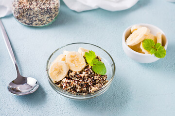 Boiled quinoa mix with banana and mint in a bowl on the table. Homemade healthy breakfast.