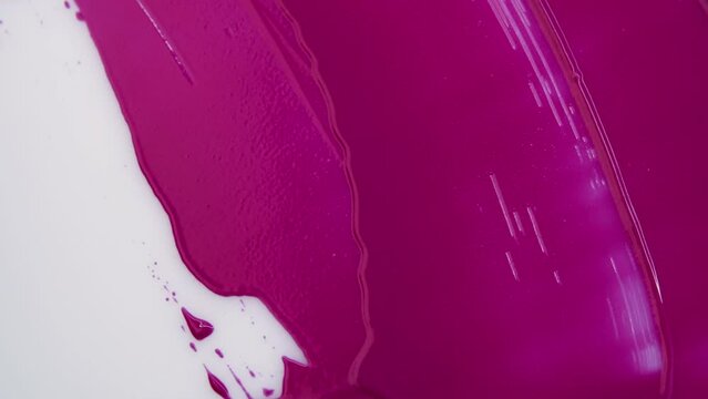 Pink lipstick. Texture of pink paint. A spatula smears magenta paint on a white background.