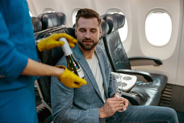 Flight attendant offering champagne to man in airplane