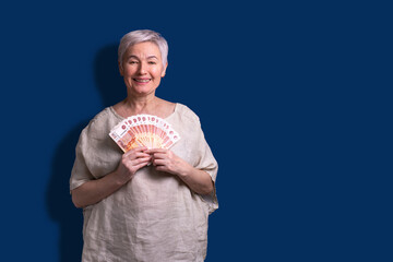 A happy elderly beautiful woman smiles with ruble bills.  Pension. Stability of earnings....