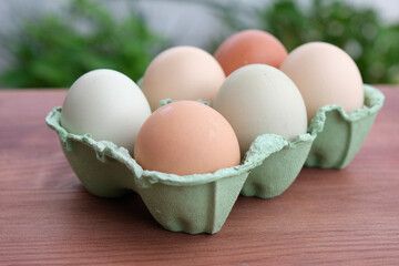 Organic raw chicken eggs in a paper box on the wooden backround. Soft focus