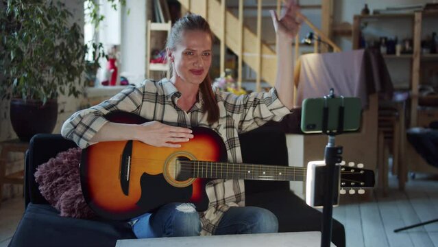 Woman recording her guitar lesson on her phone