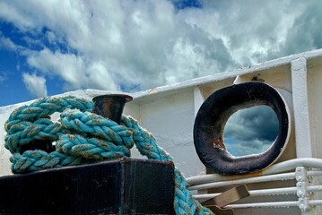 Blue hawser and bollard on board on a Norwegian ferry and cloudy sky in background.