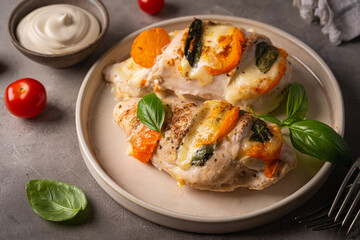 Baked Tomato, mozzarella and basil stuffed chicken breasts on gray table