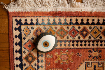 painted evil eye rock on colorful rug watching