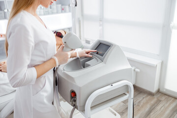 Female beautician using laser epilation machine in beauty salon