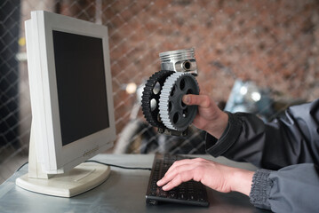 Car service worker orders a car or motorbike spare parts through the internet with the computer...