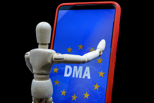 wooden mannequin touching a smartphone with the text DMA and the flag of the european union on the screen