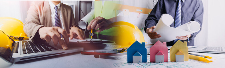 Team of architects or engineering consulting and analyzing working on objects tools and construction drawings inspection, discussing planning new architectural project on blueprint and model house.