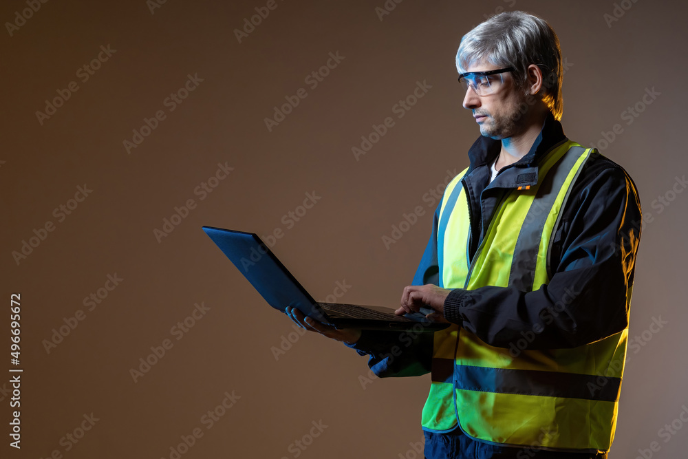 Poster builder designer. designer with laptop in hand. builder on brown background. gray-haired man with op