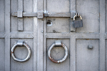 A massive metal door with a large padlock and round handles.The lock door. Armored storage door.