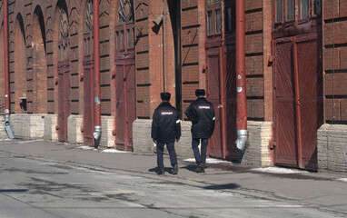 Two men in police uniforms are walking down the street near an old building. Russian police . A policeman on duty.