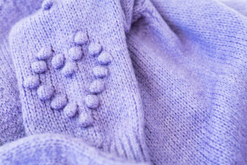 Background texture: lavender wool knitted fabric with a heart. Very peri, warm cozy sweater.