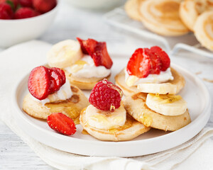 Mini pancake cereal with banana, raspberry, strawberry, honey, yogurt for breakfast. Mini pancake cereal is new trend.