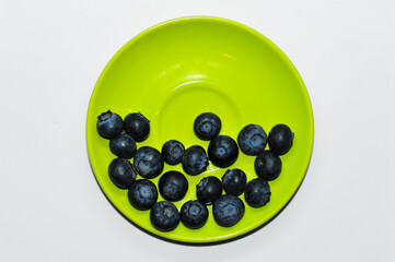 Blueberries on a plate on a white background. Signs. Healthy wholesome food. Vitamins and microelements.
