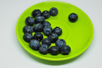 Blueberries on a plate on a white background. Signs. Healthy wholesome food. Vitamins and microelements.