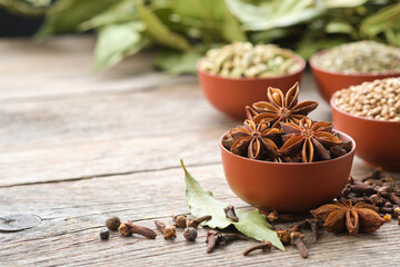 Bowl of anise stars. Bowls of aromatic spices - coriander, cardamom pods on background. Gloves,...