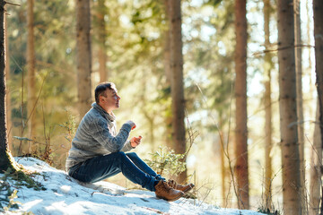 Middle aged attractive man sitting in the forest and looking up, relaxation and healthy lifestyle...