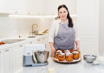 female cook with Kraffins, easter cakes and Panettones in the kitchen.