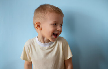 Naklejka premium Portrait little smiling boy on blue studio background. Happy child kid. Copyspace mockup banner