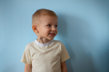 Fototapeta premium Portrait little smiling boy on blue studio background. Happy child kid. Copyspace mockup banner