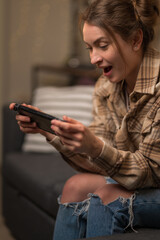 Girl gamer emotionally plays a video game on a portable game console. Close-up. Virtual reality, mobile games, cyberspace, youth culture, competition, prizes, win.