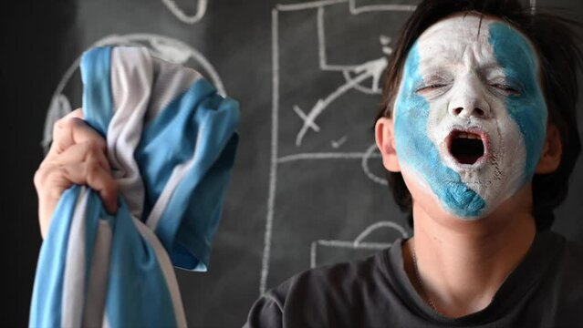 closeup of soccer fan painting the face of argentina celebrating