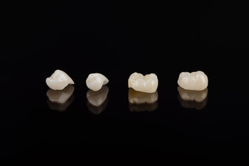 Qualified anatomic ceramic and zirconia crowns of human teeth close up macro isolated on black...