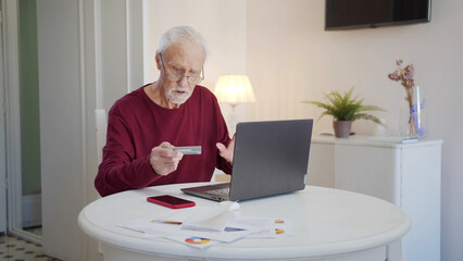 Old man struggling to pay for online purchases with a credit card