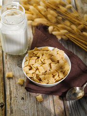 Whole grain quick breakfast - crispy cereal pads, milk and a bunch of cereals on a wooden background. Solar lighting. Quick express breakfasts, children's, school, vegetarian food. Supermarket.