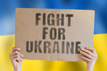 The phrase " Fight for Ukraine " is on a banner in men's hands with a blurred Ukrainian flag in the background. Punch. Rebel. Diplomacy. European. Danger. Attack. Battle. Democracy. Economy. Force