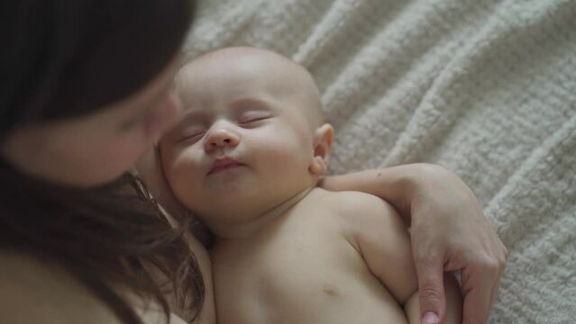 a beautiful naked baby sleeps in his mother's arms. the happiness of motherhood.