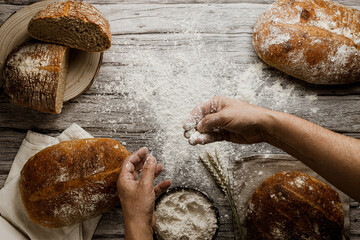 Aerial view photo of a baker's work table with artisan bread, flour, wheat and wooden boards. a baker works the loaves