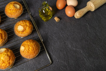 Fototapeta na wymiar freshly baked homemade muffins on a baking tray, olive oil, fresh eggs, black slate background, space for text.