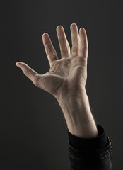 Man's hand reaching up against a dark background. Concept of helping
