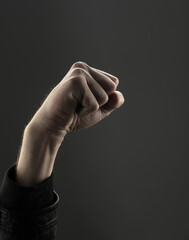 Men's hand clenched into a fist on a dark background. The concept of independence.
