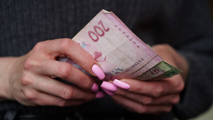 Close-up of female hands holding hryvnia banknotes, Ukrainian currency. The concept of currency exchange in another country.Tourism and travel.Selective focus.