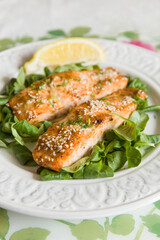 Grilled salmon served with mini spinach and a piece of lemon on white plate. Vegetarian lunch for diet.